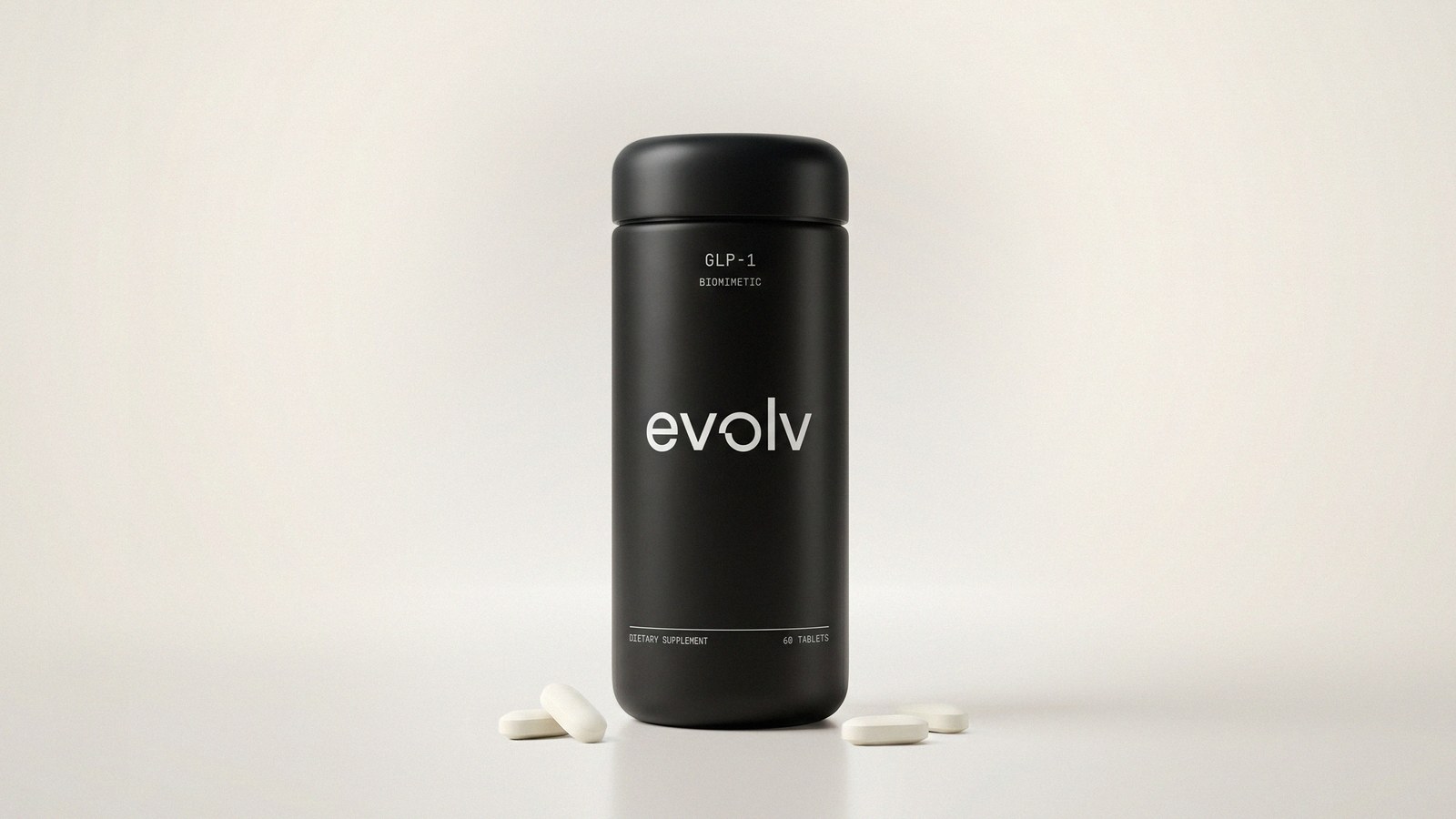 A matte black Evolv GLP-1 cylindrical supplement bottle labelled GLP-1 Biomimetic, 60 tablets, standing on a pale grey studio backdrop with four white oblong tablets scattered at its base.